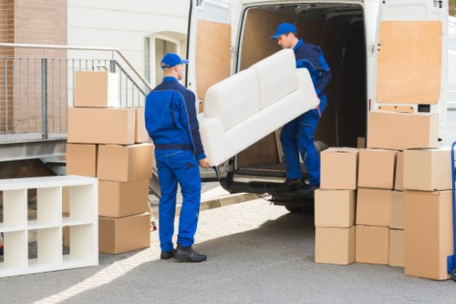 Professional movers transporting furniture through a residential area in Ickenham